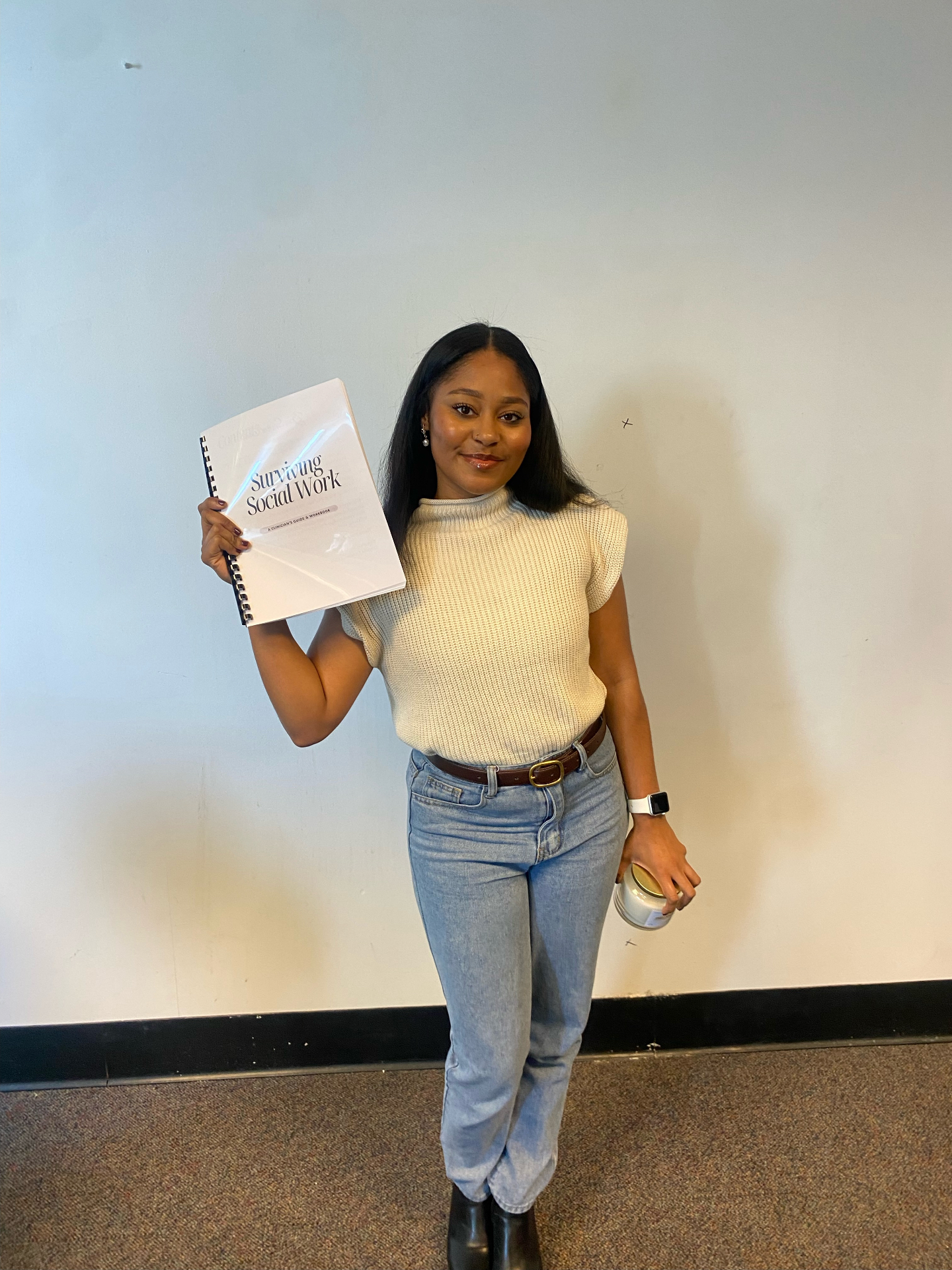 Daniela holding the Surviving Social Work workbook